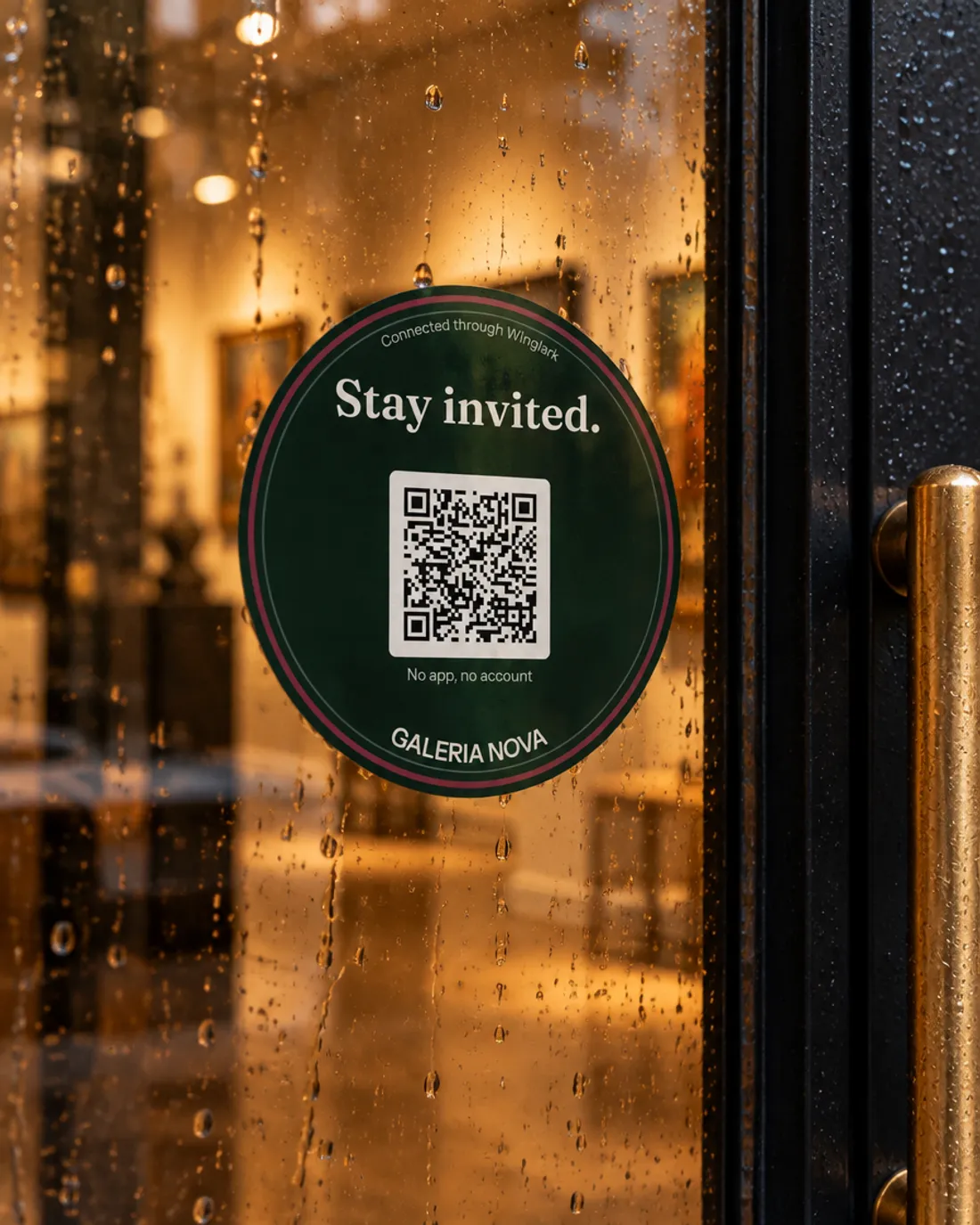 Yağmur altında bir galerinin cam kapısında, QR kodlu, yuvarlak bir “Stay invited.” etiketi